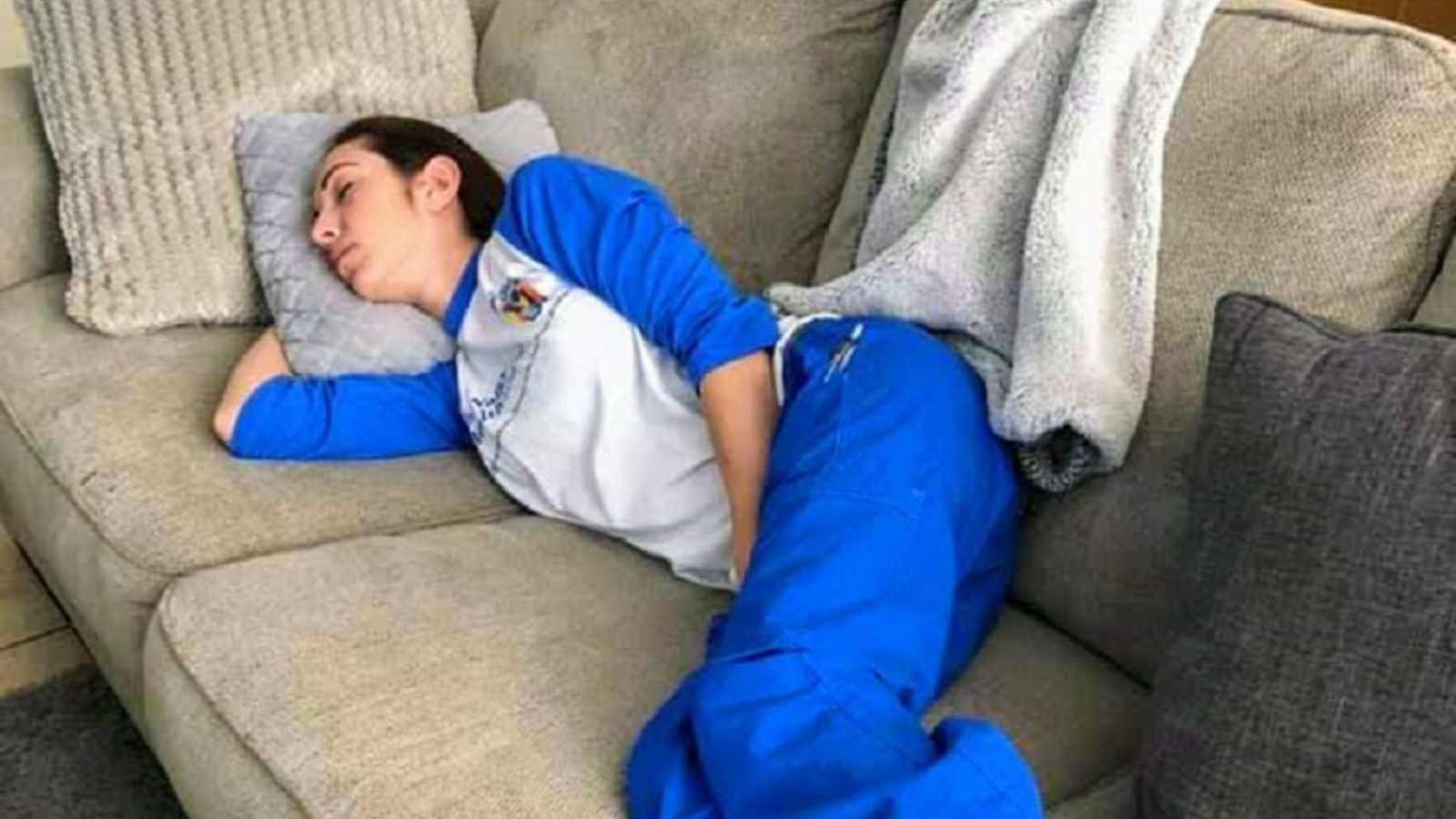 Nurse napping on couch in blue scrubs